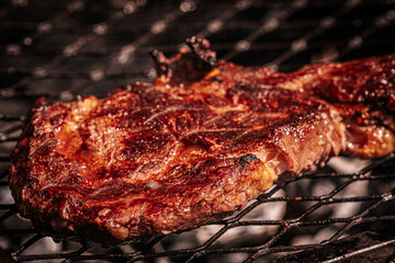 Two juicy bone-in steaks sizzling on a hot grill, one being flipped with metal tongs. Rich grill marks and charred edges highlight the heat and texture.