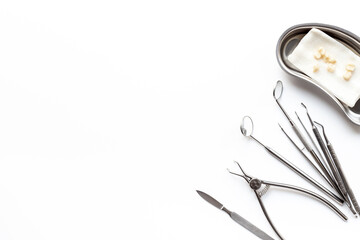 Many dental metal tools and teeth crowns in tray for dental implantation on white background. Professional Dentist tools, top view