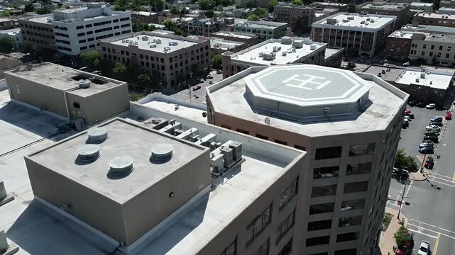 Aerial view of city building rooftops with a helipad and HVAC systems showcasing modern urban infrastructure and bustling downtown landscape from above