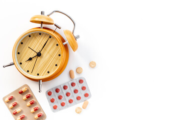Medical treatment pills and vintage alarm clock, top view. Time to take medicine concept