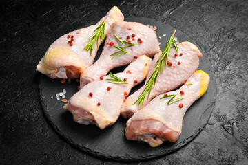 Raw uncooked chicken legs, drumsticks, ready to cook. On a textured stone background. Side view.