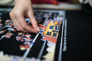 Female hand solving jigsaw puzzle close up