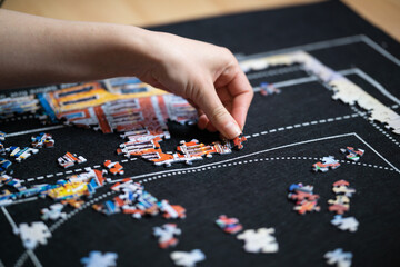 Obraz premium Female hand solving jigsaw puzzle close up