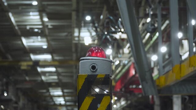 Red emergency beacon light in assembly shop of machine-building plant. Ensuring safety and warning of emergency situation and need for immediate response.