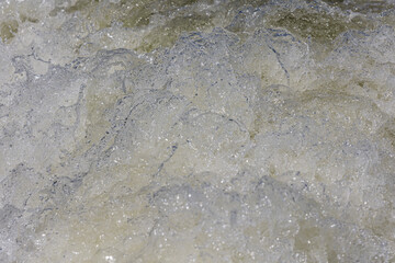 Turbulent water, showing churning foam, bubbles, and surface tension.