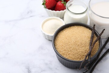 Different ingredients for panna cotta. Milk, sugar, vanilla and strawberries on white marble table, closeup. Space for text