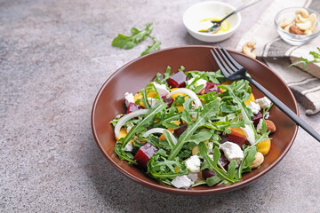 Tasty salad with arugula, cheese, peach, beetroot and nuts on grey table, closeup. Space for text