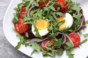 Tasty salad with arugula, vegetables, egg and seeds on grey table, top view