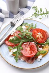 Tasty salad with arugula, cheese, tomatoes, nuts and prosciutto on white table, closeup