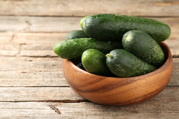 Fresh cucumbers in bowl on wooden table, closeup