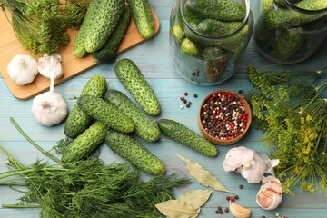 Making pickles. Fresh cucumbers and other ingredients on light blue wooden table, flat lay