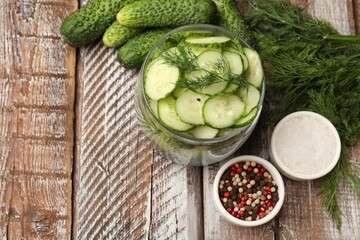 Making pickles. Slices of fresh cucumbers in open jar, spices and dill on color wooden table, flat lay