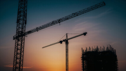 Silhouetted Construction Cranes and Building Against Dusk Sky skyscraper