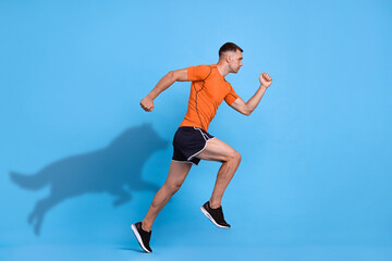 Obraz premium Athletic man running. His shadow in form of hound on light blue background. Sports poster