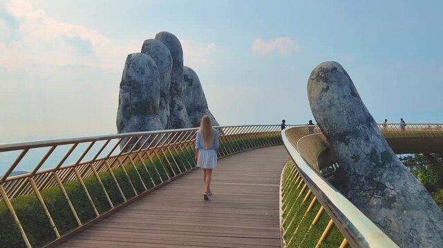Golden Bridge in Ba Na hills, Da Nang, Vietnam on a sunny day. 4K video footage. Lifted by two giant concrete hands. Iconic world famous bridge in the mountains
