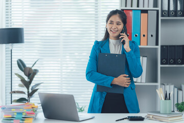 Efficient Communicator: A confident businesswoman engages in a focused phone call in her office,...