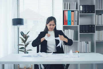 Frustration at Work: A woman in a professional setting tears documents in a display of workplace...