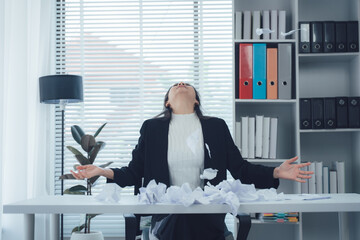 Overwhelmed by work: A professional woman is feeling a wave of defeat, with crumpled papers...