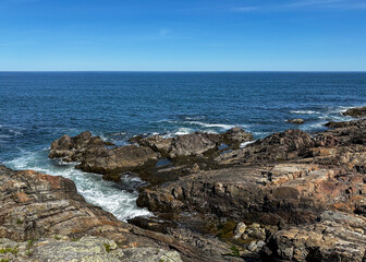 The rocky coast along Marginal Way in Ogunquit, Maine, on a beautiful summer day with a blue sky and blue water