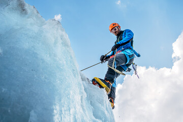Climber in vibrant colors belaying down serac on icy glacier during Lenin peak ascent under clear sky with snow-covered peaks in background. Extreme active people, high-altitude mountaineering concept
