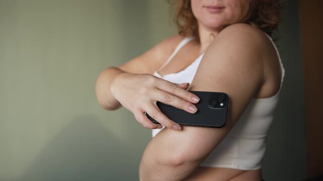 Young woman controls blood sugar level using sensor and smartphone. Continuous glucose monitor helps diabetic to independently control condition and amount of sugar in blood at home.
