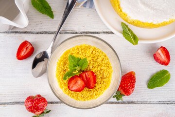 Classic cheesecake in glass, with fresh strawberry and golden cookie crumble