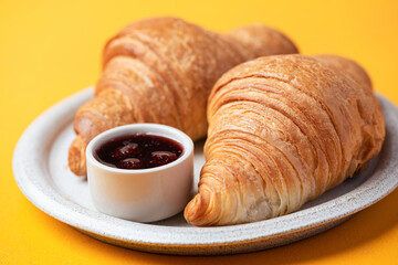 Two french croissants served with marmalade on a plate, closeup view