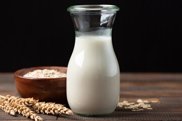 Vegan Oat Milk in a glass jar. Lactose free and dairy free alternative milk on wooden table