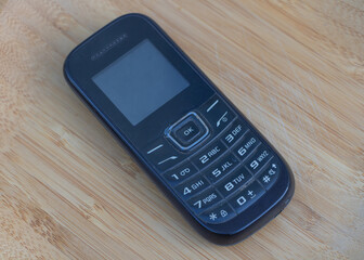 Classic black button cell phone with numeric keypad on wooden table