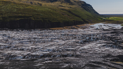 Aerial View of Icelandic Glacier with Volcanic Ash and Green Mountains