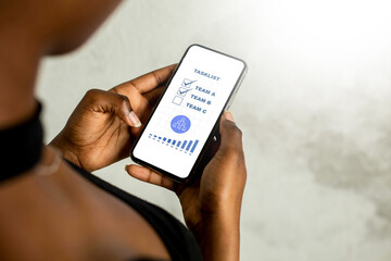 Person holding a smartphone with a task list application displayed.
