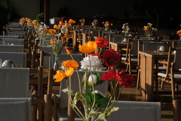 Cozy table setting with fall decor, flowers and utensils in dining room. Bouquet of fall flowers. Cozy kitchen interior. Festive table with wicker napkins, white plates and cutlery on wooden table