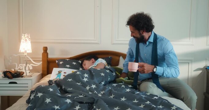 Father playfully wakes his son with a stuffed toy. Businessman wakes his son in the morning. A loving, fun moment as they begin their day. Part 2 of the &ldquo;Dad&rsquo;s Day&rdquo; series.