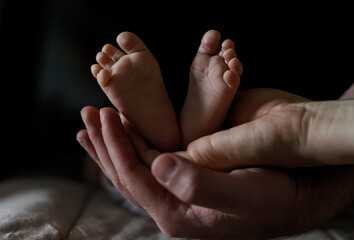 Baby's little feet in the hands of both parents