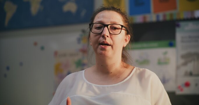Female Teacher Giving Lecture, Talking to Schoolchildren, Explaining Assignments for the Lesson to Students. Woman Educating Science or Mathematics in Modern Colorful Classroom. Close Up Portrait View - Powered by Adobe