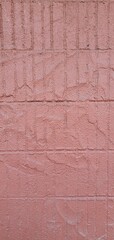 Close-up of a textured pink stucco wall with visible grid-like patterns and rough surface details, ideal for use as a background or texture in architectural and design projects.