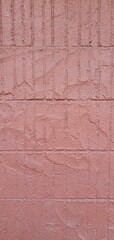 Close-up of a textured pink stucco wall with visible grid-like patterns and rough surface details, ideal for use as a background or texture in architectural and design projects.