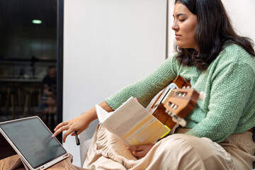 Singer songwriter composing new music at home with digital tablet and guitar