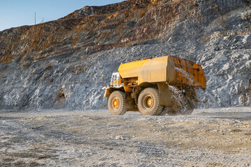 Obraz premium Anti-dust watering Dump Truck in Open-Pit Mine Against Rocky Terrain.