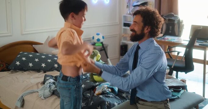 Business dad helps his son get dressed for school in the morning. A warm and loving moment of care, bonding, and everyday routine. Part 9 of the &ldquo;Dad&rsquo;s Day&rdquo; series.