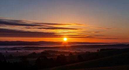 Fototapeta premium Glowing Orange Sunrise Over Rolling Landscape Hills