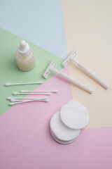 Fototapeta premium White razor with cotton pads and sticks, face cream or serum on pastel background. Self-hygiene, beauty concept.
