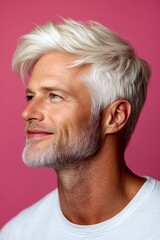 Fototapeta premium A happy man in a studio photo. Pink solid background. Visual idea artwork of style for aging men. Classy men's side part haircut - midlife white man with white hair.