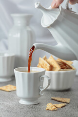 Black coffee in white porcelain cup and crunchy square crackers.