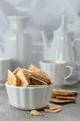 Crunchy square crackers and coffee in white porcelain cup.