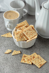 Black coffee in white porcelain cup and crunchy square crackers.
