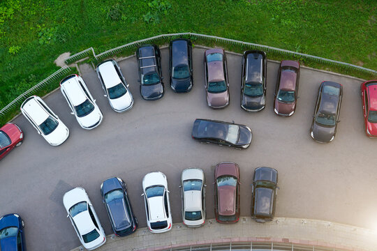 Multiple cars occupy a crowded parking lot with various colors and sizes. One vehicle is maneuvering to find a spot, illustrating active parking dynamics in a well-used area