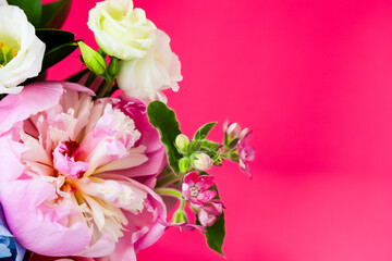 Colorful bouquet of peonies and roses against bright pink background enhancing floral beauty