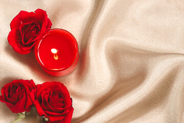 Romantic candlelight setup with red roses on a soft golden fabric for a cozy evening