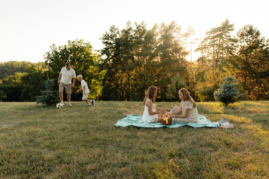 A family shares time outdoors, with a picnic and a father-son soccer activity. - Powered by Adobe